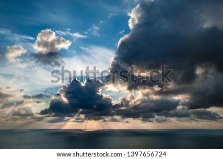 Clouds over the sea. Beautiful sunset over the sea. Sun rays through the clouds. Thunderclouds.