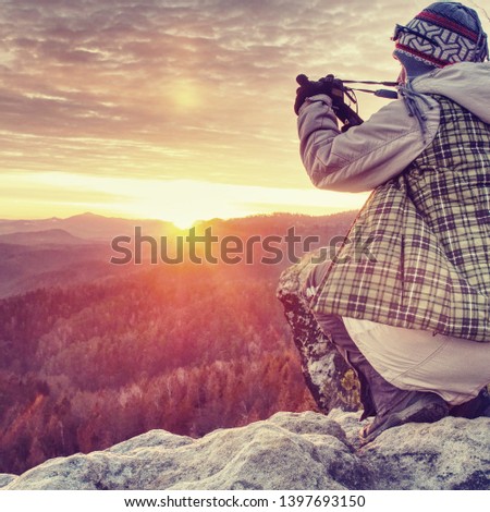 Photographer taking picture. Woman artist photo enthusiast stay with camera above valley and works. Nice view over dried trees in valley.