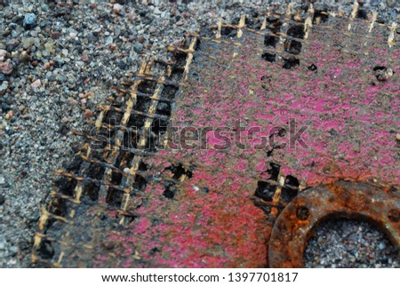Photograph of a background with an old rusty metal circle with rubbed red paint with twisting rods