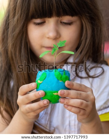 Cute little girl protect world. Save the earth concept. Focus on planet with green plant. 