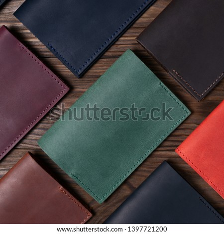 Seven handmade leather passport covers on wooden textured background. Up to down view. Stock photo of luxury accessories.
