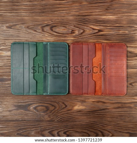Two  handmade leather  opened porte-monnaie on wooden textured background. Up to down view. Stock photo of luxury accessories.