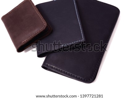 Handmade brown cardholder, blue passport cover and black purse isolated on white background closeup. Stock photo of isolated handmade luxury accessories.