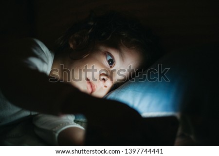 Beautiful baby girl watching smart phone before sleeping