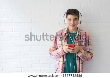 young or teen with mobile phone and earphones on the white wall