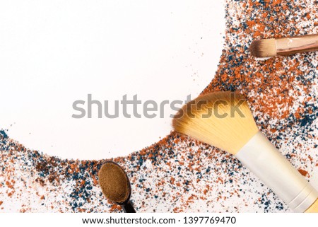 Makeup brushes on a white background, with traces of cosmetics forming a frame.
