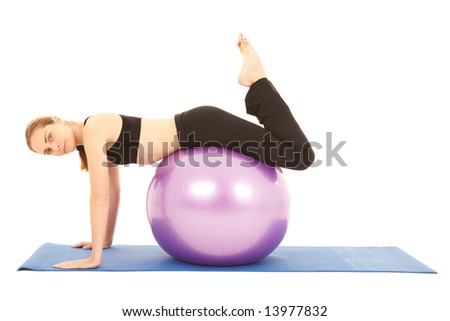Fit young brunette pilates instructor showing different exercises on a white background with basic pilates equipment including a ball and yoga mat. White background, not isolated