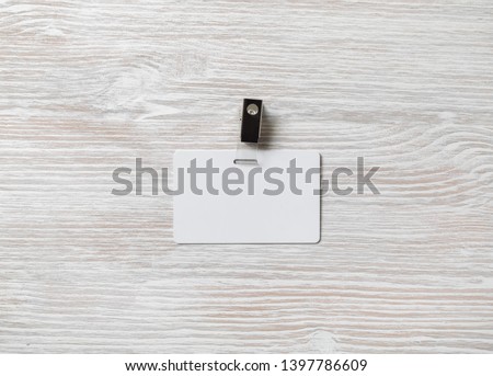 Blank plastic badge mockup on light wooden background. White id card. Space for text.Flat lay.