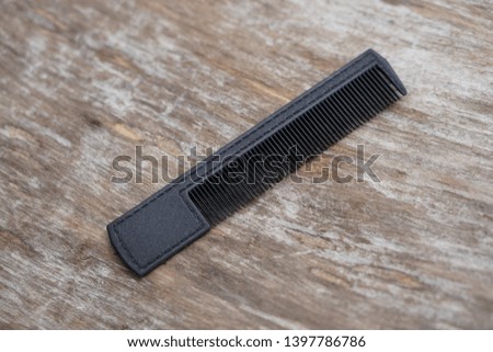 Black hairbrush on the background of wooden boards. fashionable theme. Photo for design