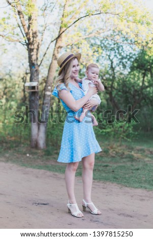 Mom gently holding infant girl offspring and standing on country road outdoors artistic photograph
