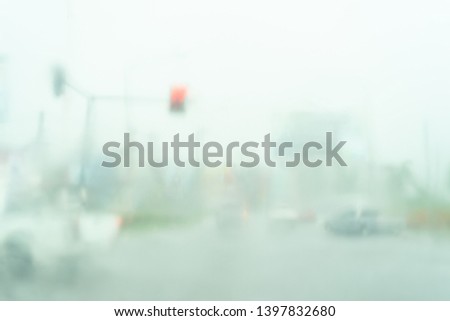 Blurred photo of traffic in traffic light in rainy day.Heavy raining in the road are wet.To be safe, slowly and carefully on driving.Rainy season concept.
