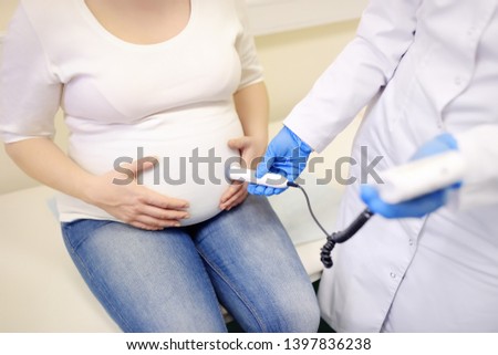 Doctor using fetal droppler device for listening baby heartbeat on clinic. Medical insurance childbearing. Family doctor for gestation. Maternity leave. Health care and medicine. Royalty-Free Stock Photo #1397836238