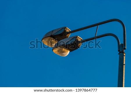 Doubled street lamp closeup in front of the clear blue sky with copyspace