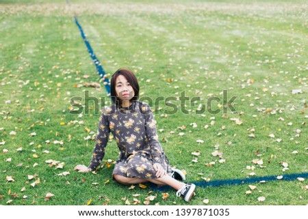 a young asian girl sitting on the football ground autumn