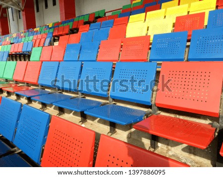 View of stadium with empty seat. Colorful seat in soccer stadium when holiday. Blue, green, red and yellow iron seats. Landscape of free arena seating.  