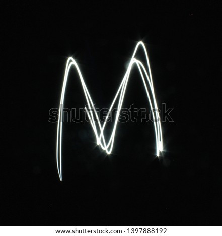 M-created by light letters - uppercase character, Pictured by light letters, painted by light, Black background light font,​selective​ focus