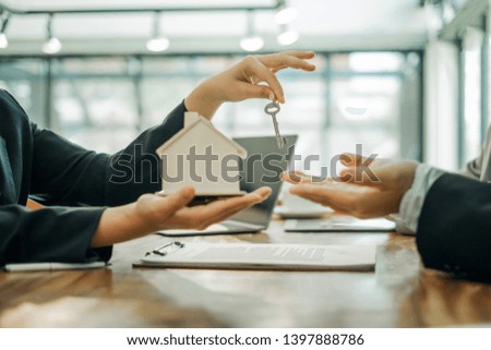 Real estate agents holding model house and keys for submit documents for customers to sign for a sale contract,real estate concept.