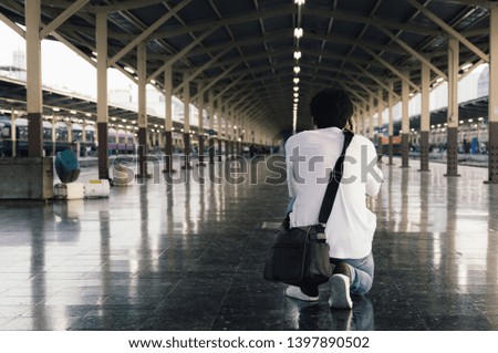 A man was kneeling to take a picture at the train station.