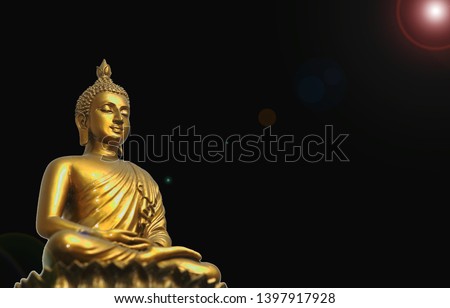 The Buddha statue isolated on dark background with lense flare.