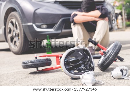 scared and stressed desperate drunken driver and bottle of beer in front of automobile crash car with child bike after traffic accident in city road