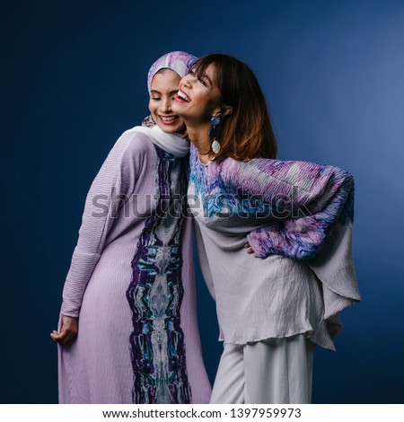Portrait of two Middle Eastern Muslim women in festive ethnic Raya clothing posing in a studio. They are both young, attractive and beautiful. The women are friends or relatives.  Royalty-Free Stock Photo #1397959973