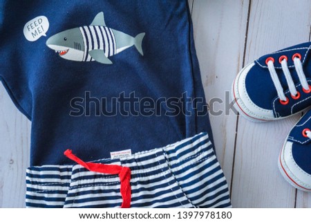 Cute blue tone newborn apparel for small boy on the light wooden texture.