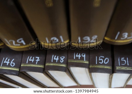 Closeup shot of traditional brown serial hard cover academic books on book shelves in library. Concept of old style knowledge reference resources in modern-day library