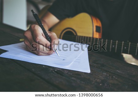 songwriter artist thinking writing notes,lyrics in book at studio.man playing live acoustic guitar.concept for musician creative.artist composer in work process.people relaxing time with instrument Royalty-Free Stock Photo #1398000656