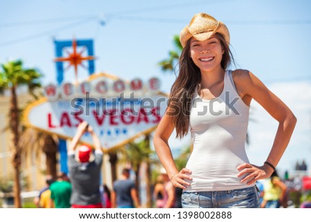 Las Vegas sign american tourist cowgirl woman on USA road trip travel wearing cowboy hat in front of famous tourism attraction on The Strip. Welcome to Fabulous Las Vegas, Nevada, Summer vacation.