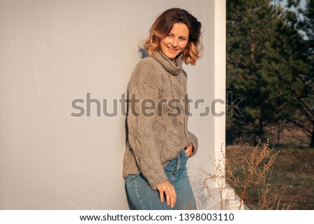 Portrait of a beautiful young model in knitted hat  and warm clothes enjoy day, on background field in  sunny autumn day . Autumn warm photo. 