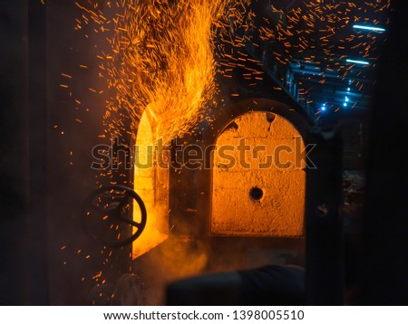 The boiler's door open by worker for manual firewood feeding 