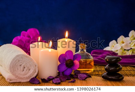 Spa setting healthcare items colorful massage items blue color spa background
with burning candle and orchid flower