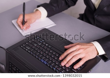 Businessman write in paper documents over the laptop keyboards. Men hands on laptop top view close-up.