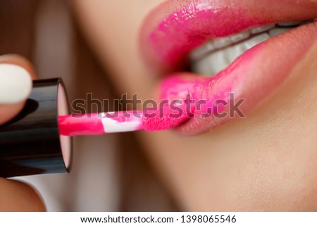 a woman paints her lips with a brush. close-up photo