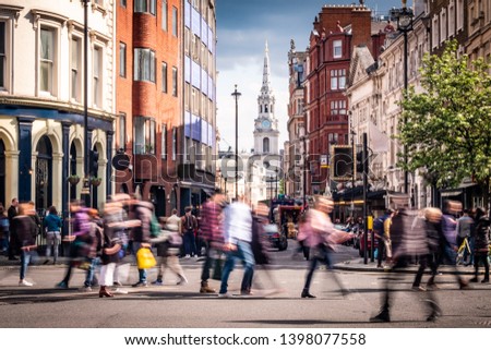 Motion blurred crowds of people crossing road in London's West End  Royalty-Free Stock Photo #1398077558
