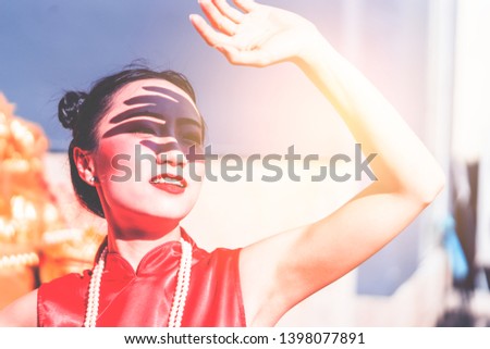 Chinese woman is holding hand up to protect from the sun light in hot summer day for skin care Royalty-Free Stock Photo #1398077891