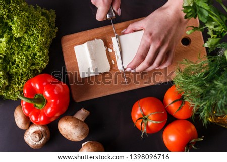 young woman slicing cheese in a gray apron