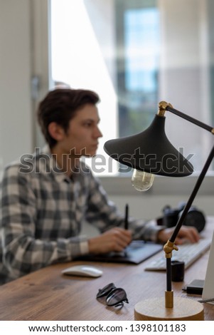 Young man working on computer in office interior, out of focus