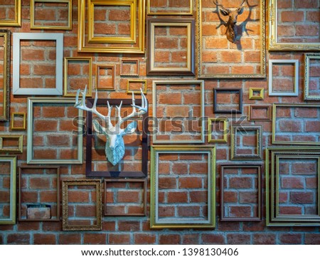 Various empty photo frames with plaster deer head hanging on brick wall. Brick wall decoration concept.