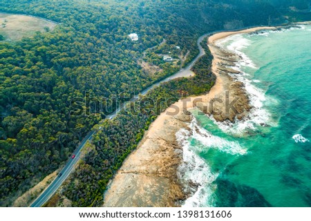 Aerial view of vehicles driving on Great Ocean Road along scenic coastline near Lorne, Australia