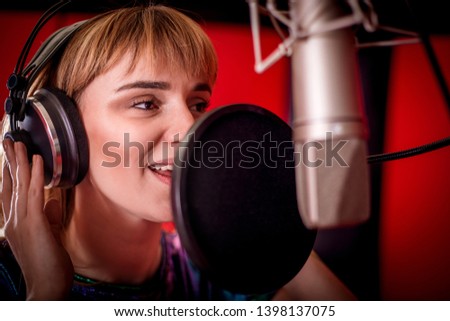 Female singer with microphone recording a song in music studio