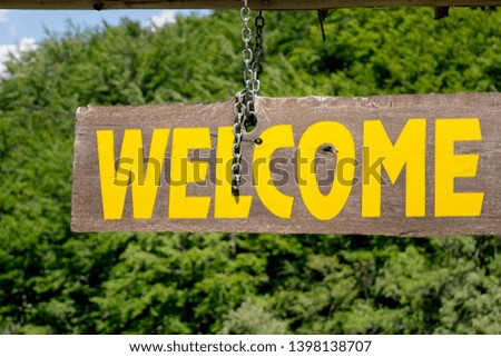 Welcome inscription by yellow paint on wooden board,