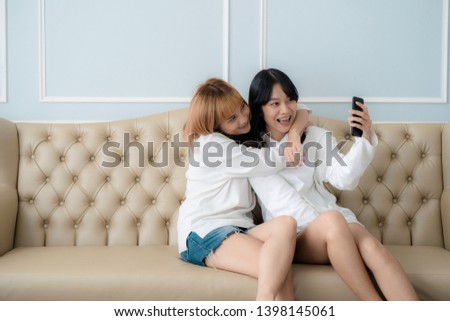 Happy couple friend sitting on sofa hug and using phone taking selfie together at home. Friend and lesbian concept.