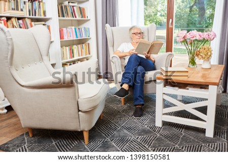 Senior woman reading concentrated in a book in a chair in the senior residence
