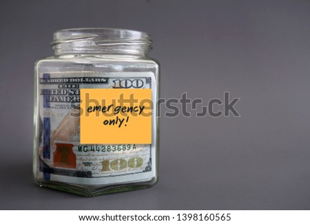Money glass jar with written sticky note EMERGENCY ONLY! on gray blank background can used as copy space. Concept of Emergency Fund saving goal, financial security for rainy day Royalty-Free Stock Photo #1398160565