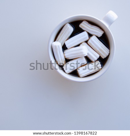 Cup of black coffee with marshmallow on a white background. Top view.
