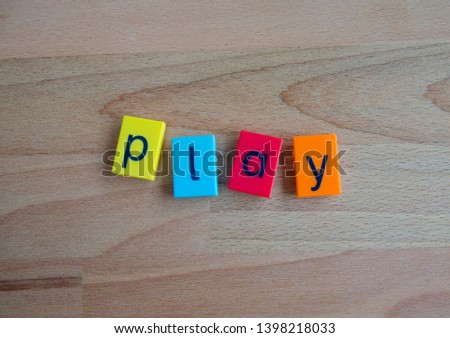 Toy lettering block in different colors on a wooden background that reads the word play