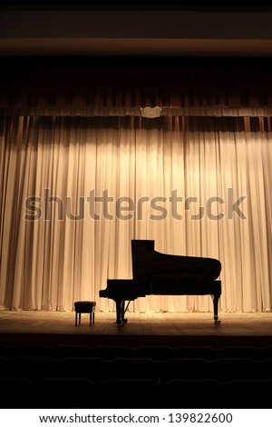 Concert grand piano at theatre stage with brown curtain