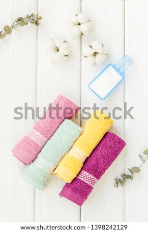 preparing for laundry with washing powder and towels on white wooden background top view