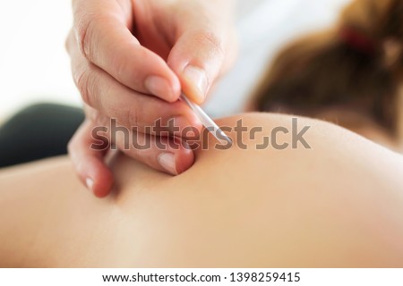 Close-up of young physiotherapist doing a trigger point injection in patient back. Royalty-Free Stock Photo #1398259415